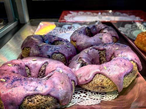 Four purple-glazed donuts with a textured surface, displayed on a decorative tray.
