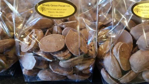 Bags of chocolate-covered pecans from Shady Grove Pecan Co., labeled with contact information and a playful tagline.