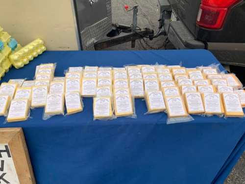 A table covered with neatly arranged packages of cheese, each labeled with a white tag.