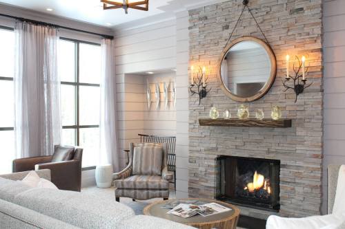 Cozy living room with a stone fireplace, modern decor, and large windows letting in natural light.