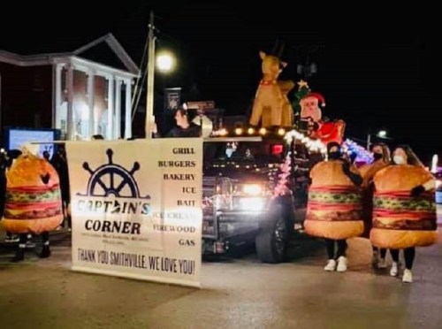 A festive parade float featuring Santa, a reindeer, and people in burger costumes, promoting Captain's Corner.