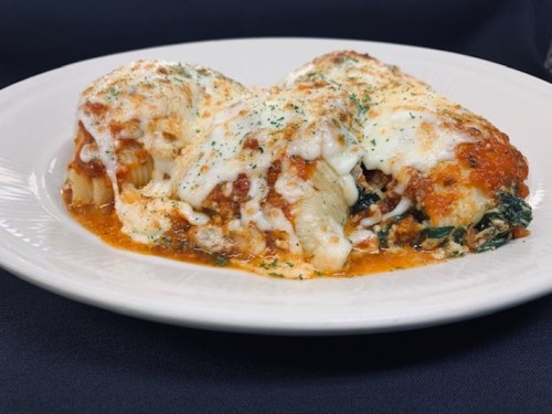 Three stuffed pasta shells topped with marinara sauce and melted cheese, garnished with herbs on a white plate.