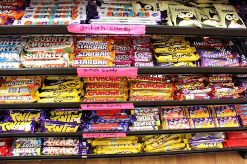 A display of various British candy bars on shelves, labeled with pink signs indicating "British Candy."