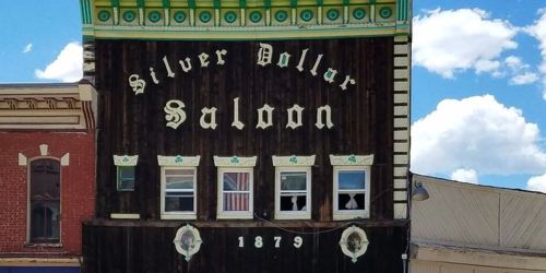 Historic building facade of the Silver Dollar Saloon, featuring wooden architecture and broken windows.