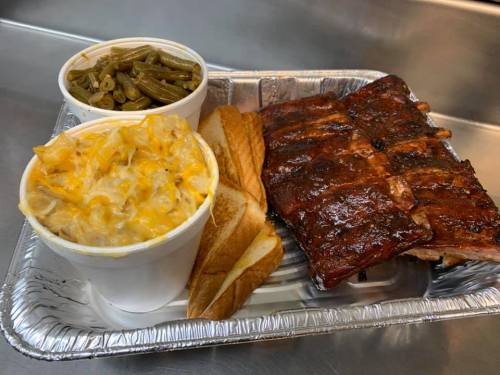 A tray with BBQ ribs, macaroni and cheese, green beans, and two slices of bread.