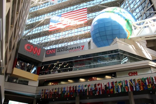 Interior of CNN headquarters featuring a large globe, American flag, and international flags hanging from the ceiling.