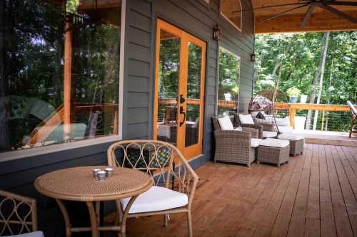 A cozy porch with wicker furniture, a round table, and large windows overlooking a green landscape.