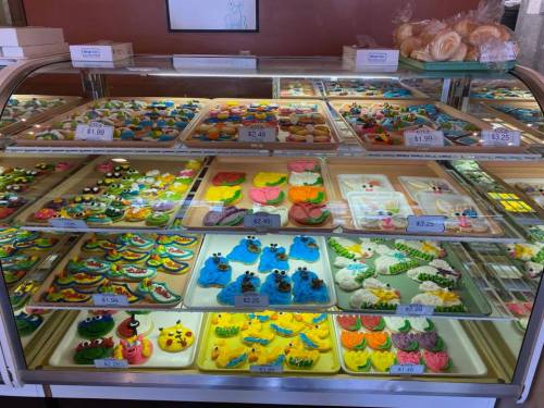 A colorful display of assorted pastries and cookies in a bakery case, featuring vibrant icing and playful designs.