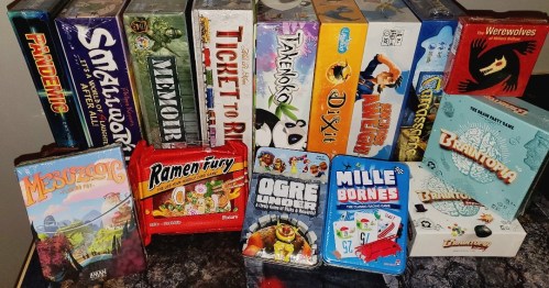 A collection of board games and card games displayed on a table, featuring colorful boxes and various titles.