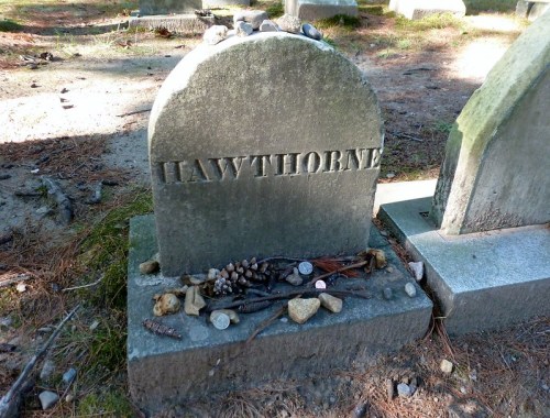Gravestone marked "Hawthorne" with natural items like stones and pinecones arranged at its base in a cemetery.