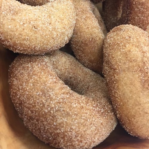 A close-up of freshly baked cinnamon sugar donuts stacked in a bowl.