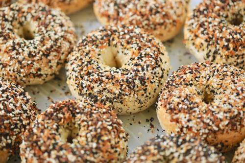 A close-up of freshly baked bagels topped with a variety of seeds, including sesame and poppy seeds.