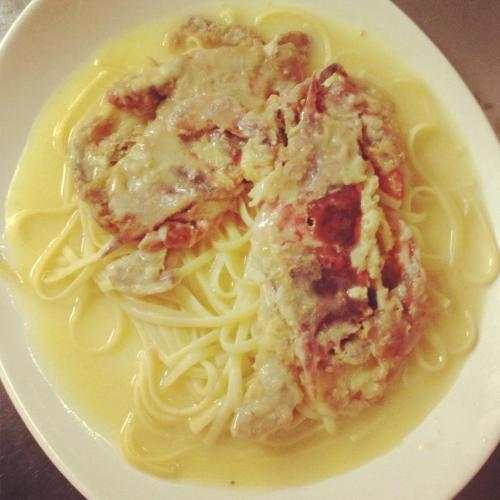 A plate of spaghetti topped with pieces of meat in a creamy sauce.