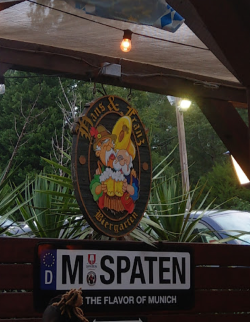 Sign for "Hans & Franz Biergarten" featuring cartoon characters, with a "Spaten" sign below it.