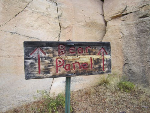 Wooden sign with red lettering pointing to "Bear Panel," set against a rocky background.