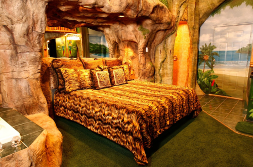 A unique bedroom with a cave-like design, featuring a patterned bedspread and tropical-themed decor.
