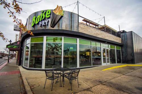 Exterior of Boise Fry, featuring large windows, a patio with tables, and a modern design on a cloudy day.