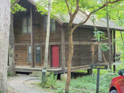 A wooden cabin with a red door, surrounded by trees, on a path labeled "13 Low Moon."