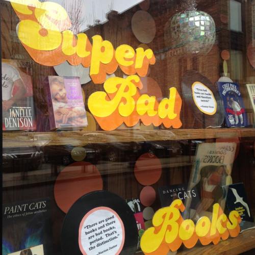 Colorful bookstore window display featuring the words "Super Bad Books" and various book covers.