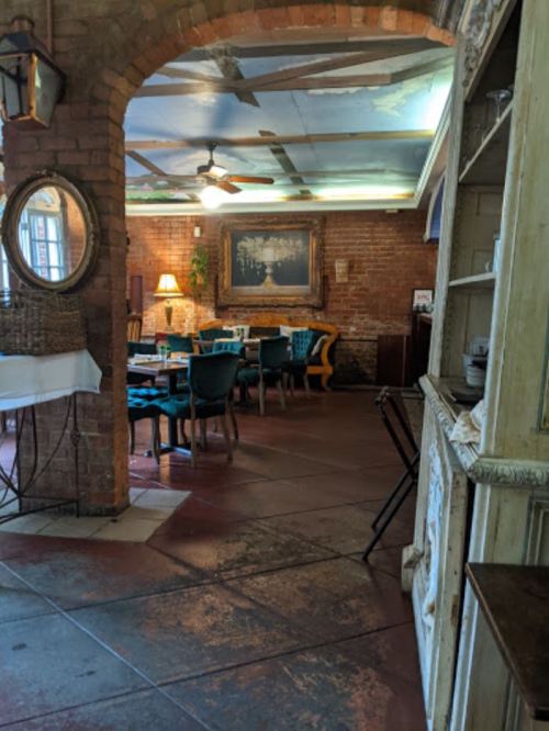 Cozy restaurant interior with brick walls, blue chairs, a large painting, and a warm ambiance.