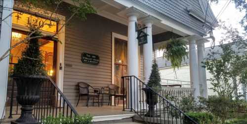 A charming porch with two chairs, potted plants, and a sign for "The Inn at the Olde Mill."