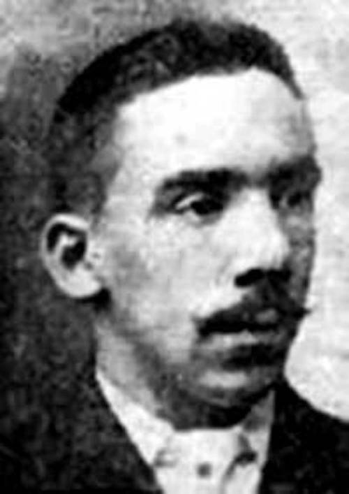 Black and white portrait of a man with a mustache, wearing a suit and looking to the side.