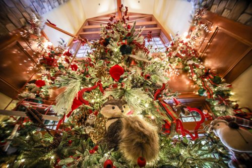 A beautifully decorated Christmas tree adorned with red ornaments, greenery, and whimsical animal figures.