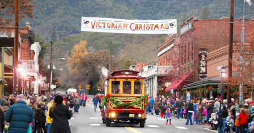 A festive street scene with a vintage trolley and a "Victorian Christmas" banner, surrounded by holiday decorations and crowds.