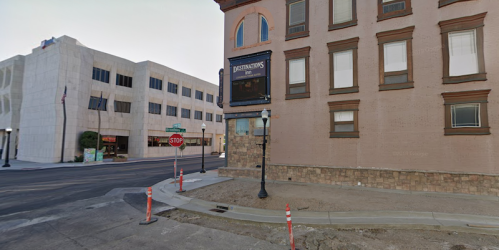 Street view of a corner building with a sign for "Destinations" and a nearby stop sign, under clear skies.
