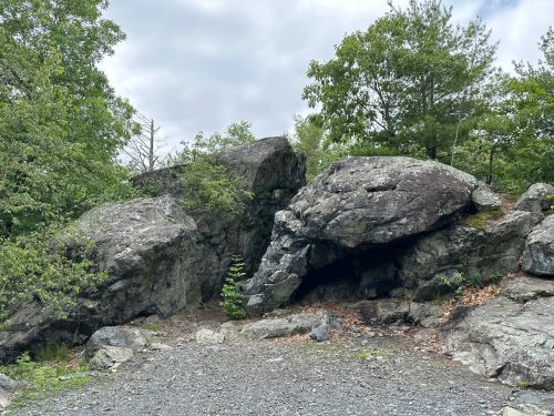 Two large boulders surrounded by greenery and trees, with a gravel path in the foreground.