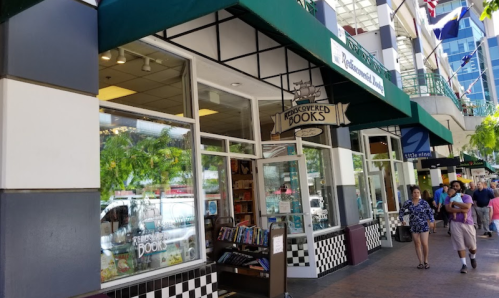 A bookstore with a green awning and large windows, displaying books and a sign that reads "Discovered Books."