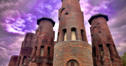 A tall, brick castle with cylindrical towers under a dramatic purple sky.