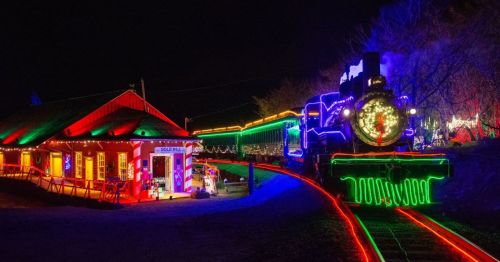 A brightly lit train and station decorated with colorful lights at night, creating a festive atmosphere.