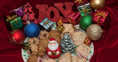 A festive display of cookies, a Santa figurine, and colorful ornaments surrounded by wrapped gifts and a "Joy" sign.