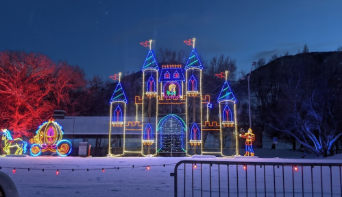 A brightly lit castle with blue towers and colorful decorations, set against a twilight sky and snowy ground.