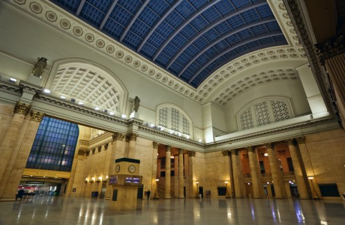Interior of a grand train station featuring high ceilings, ornate architecture, and large windows.