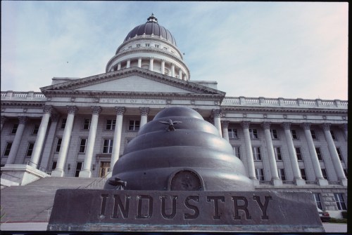 A large beehive sculpture labeled "INDUSTRY" in front of the Utah State Capitol building.
