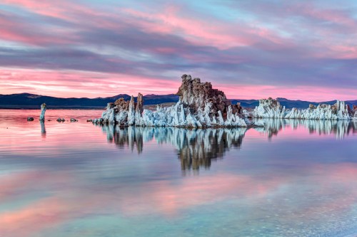 Serene landscape of tufa formations at Mono Lake, reflecting colorful skies at sunset.