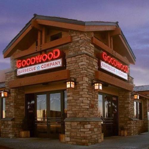 Exterior of Goodwood Barbecue Company, featuring a rustic stone facade and illuminated signage at dusk.