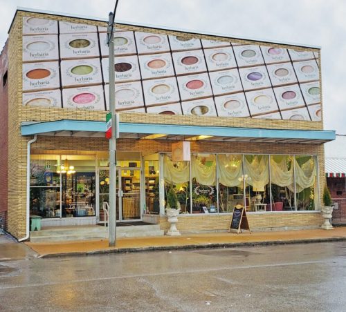 A charming storefront with large windows, featuring a colorful mural of ice cream flavors above the entrance.