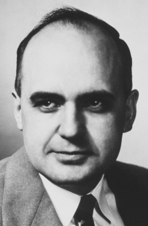 Black and white portrait of a man in a suit, with a serious expression and short, receding hair.