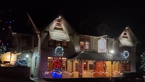 A cozy restaurant illuminated with festive lights and decorations at night, creating a warm holiday atmosphere.
