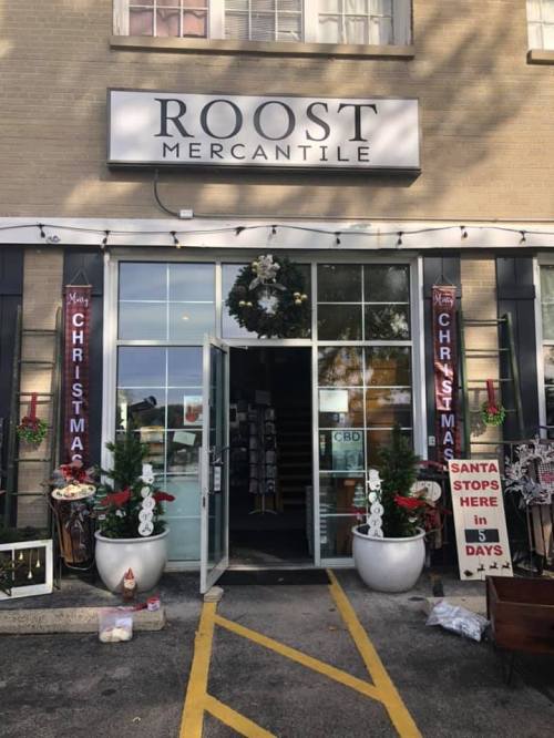 Entrance of Roost Mercantile decorated for Christmas, featuring wreaths, signs, and festive displays.
