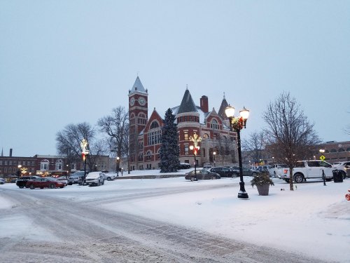 Snow-covered town square featuring a historic clock tower and festive street lamps.