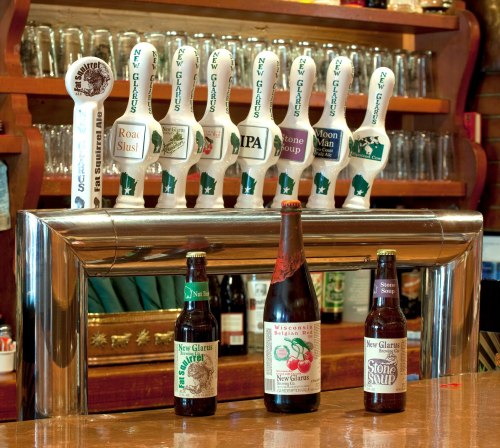 A bar with various beer taps and bottles from New Glarus Brewing Company displayed on the counter.