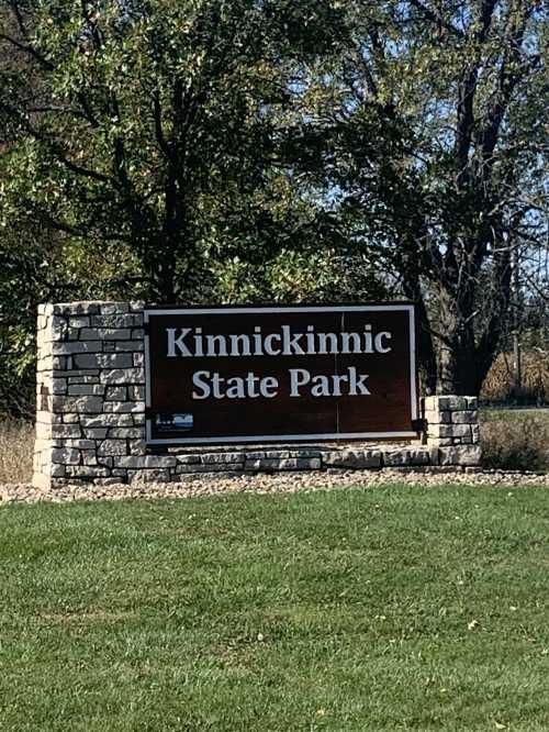 Sign for Kinnickinnic State Park, surrounded by grass and trees on a sunny day.