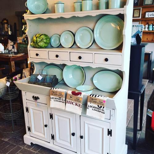 A vintage-style wooden cabinet displaying light blue dishes and decorative items on shelves.