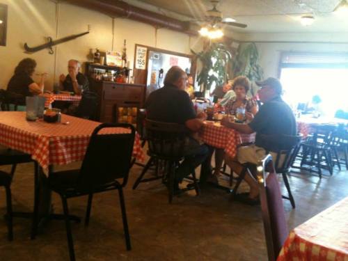 A cozy restaurant with checkered tablecloths, featuring diners enjoying meals and drinks in a casual setting.