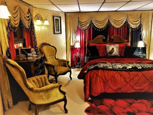 Cozy bedroom with a red and black color scheme, featuring elegant furniture, decorative curtains, and floral accents.