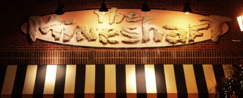 Sign for "The Mineshaft" restaurant, featuring a textured design and striped awning below.